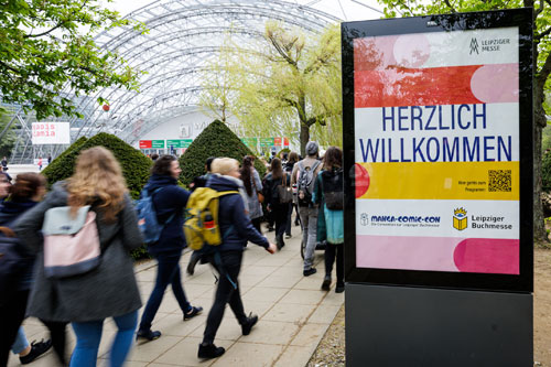 Besucher:innen der Buchmesse laufen Richtung Glasshalle. Foto: Leipziger Messe/Jens Schlüter